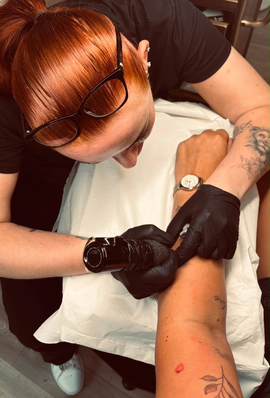 Imogen Nia tattooing a client's arm during a fine line appointment